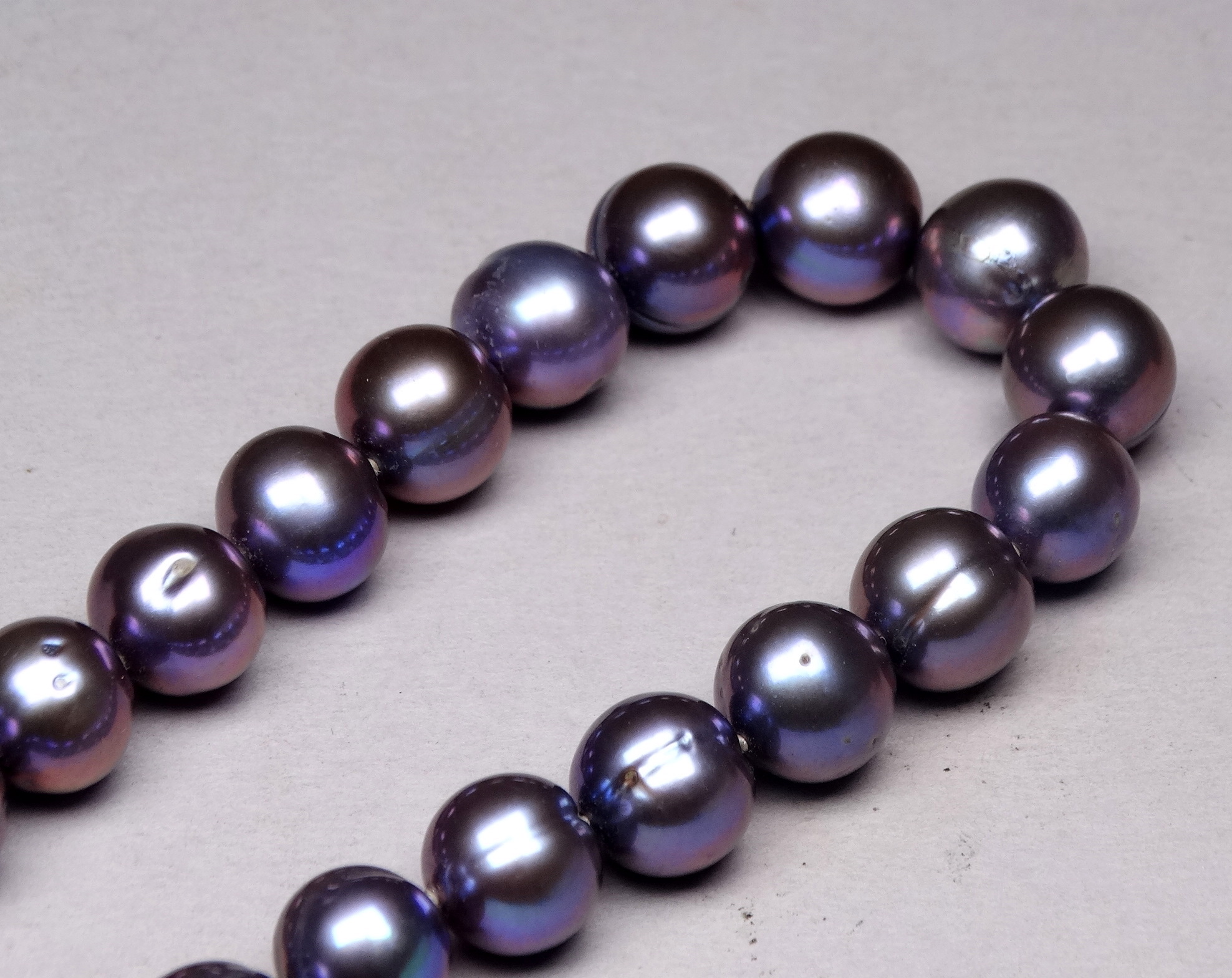 A string of uniform black Tahitian pearls - with a yellow metal S shaped clasp, possibly 9ct. - Image 3 of 3