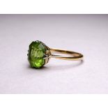 An 18ct yellow gold ring set with peridot - the emerald cut stone with a claw setting, ring size