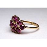 A 9ct yellow gold garnet cluster ring - with an arrangement of thirteen claw set stones, ring size