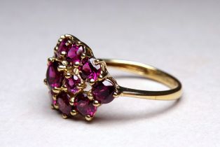 A 9ct yellow gold garnet cluster ring - with an arrangement of thirteen claw set stones, ring size