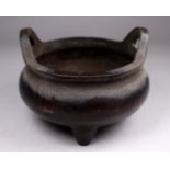 A 19th century Chinese bronze censer - of squat cauldron form with a pair of handles and raised on