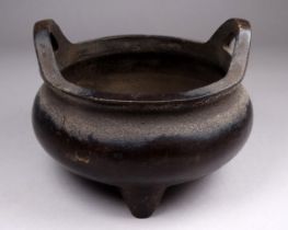 A 19th century Chinese bronze censer - of squat cauldron form with a pair of handles and raised on