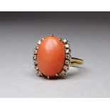 An 18ct yellow gold coral and diamond dress ring - the cabochon polished oval stone flanked by