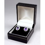 A pair of amethyst and cubic zirconia ear studs - the central oval stones within a claw set band,