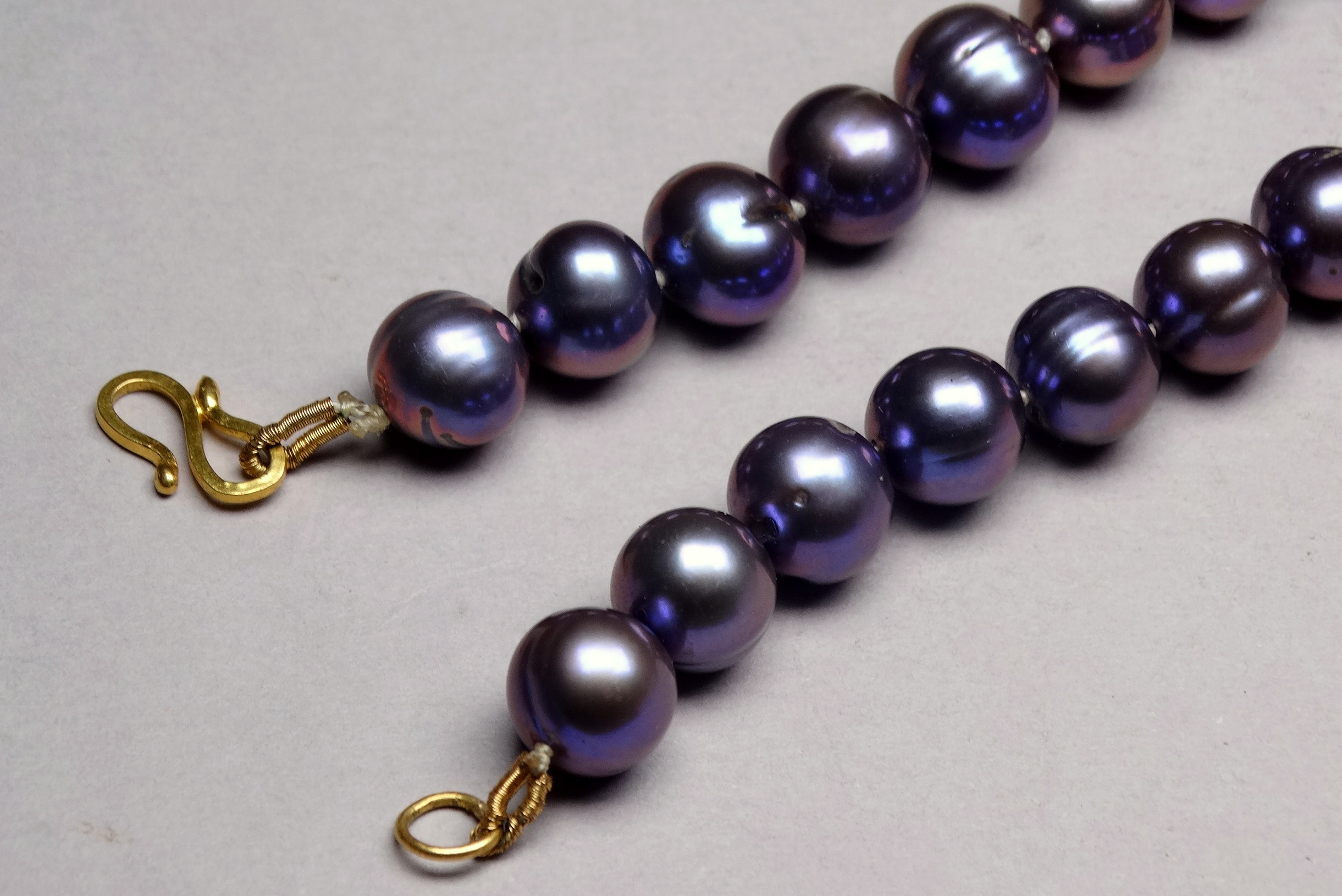 A string of uniform black Tahitian pearls - with a yellow metal S shaped clasp, possibly 9ct. - Image 2 of 3