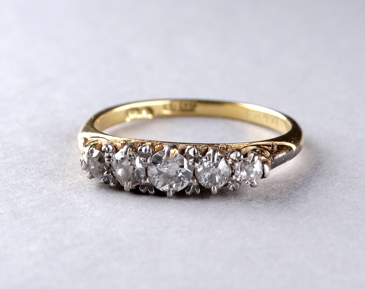 A five stone diamond ring - with a foliate scroll setting on an 18ct yellow gold band, ring size