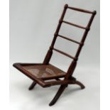 An Edwardian turned walnut low seat folding chair - with a cane seat.
