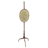 A 19th century mahogany pole screen - with an oval embroidered faceguard on a turned support