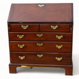 A George III mahogany bureau - the cleated fall enclosing an arrangement of drawers and pigeon holes