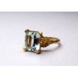 A 9ct gold aquamarine ring - the emerald cut stone within a floral setting, size N, weight 3.6g.