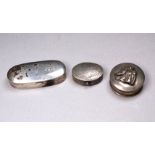 An oval silver hinged box - width 4.8cm, together with two white metal hinged boxes.