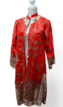 A Chinese red silk gown - decorated with gold wire showing figures, pagodas, landscape and clouds,