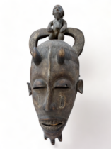 An African mask with a carved figure atop - height 72cm.