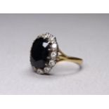 A 9ct gold sapphire and diamond set ring - the oval cut stone within a band of diamonds, size N,
