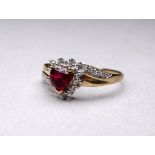 A 9ct gold ruby and diamond ring - with a heart shaped stone and crossover setting, size V, weight