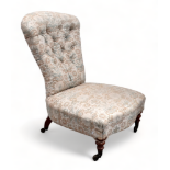 A Victorian walnut and button upholstered spoon back nursing chair - raised on short turned legs.