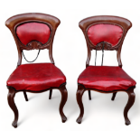 A pair of early Victorian side chairs - covered in red fabric, with overstuffed seats and cabriole