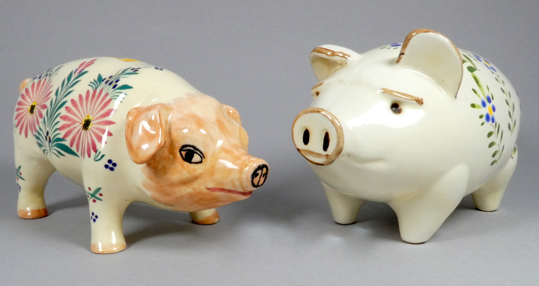 A Quimper pottery piggy bank - decorated with flowers, 21cm wide, together with another larger