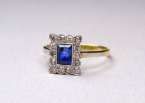 An 18ct gold sapphire and diamond set ring - in the Art Deco style, the central emerald cut stone