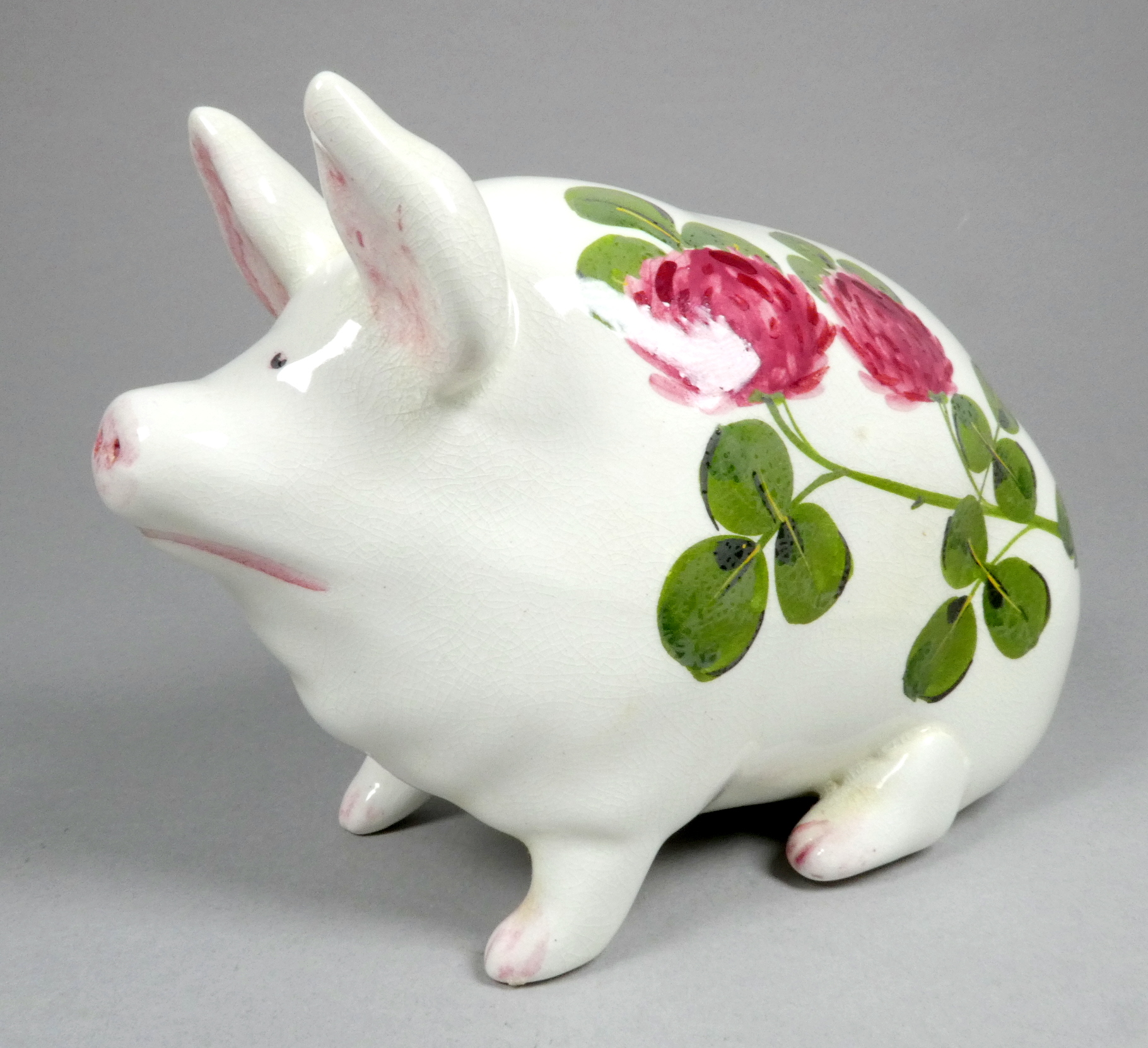 A Wemyss ware pottery pig - decorated with clover flowers, 17cm wide