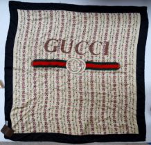 A Gucci silk scarf - floral design on a cream ground with black boarder and logo to centre, swing