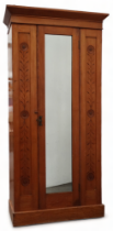 An early 20th century ash wardrobe - the cornice above a central mirror door flanked by carved