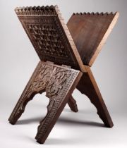 A late 19th century carved Quran stand - folding X frame, decorated with flower head and geometric
