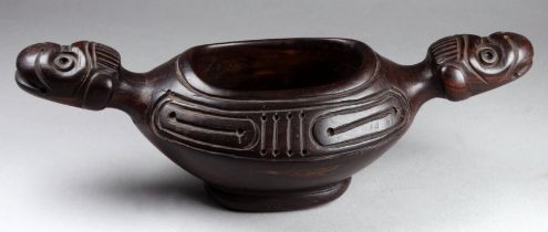 An Indonesian hardwood bowl - of oval form with twin monkey head handles, 23cm wide