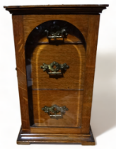 An Edwardian oak smoker's cabinet - with an arrangement of three drawers behind an arched bevelled