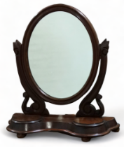 A Victorian mahogany toilet mirror - oval within shaped carved supports and a plinth base