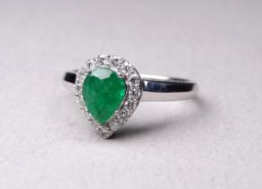 A 9ct white gold emerald and diamond ring - with pear shaped central stone within a band of