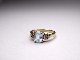 A 9ct gold aquamarine and diamond ring - the oval central stone flanked by diamond heart shaped
