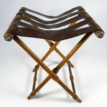 A late 19th century turned beech campaign stool - with a webbed tan leather seat and turned