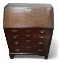 A George III oak bureau - the cleated fall enclosing an arrangement of drawers, pigeon holes and