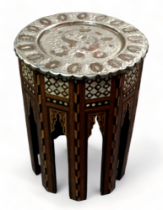 A late 19th century Middle Eastern table - the circular tinned copper repousse top decorated with