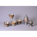 FOUR TIBETAN WOOD AND WHITE METAL TEA BOWLS, A TEA BOWL, COVER AND STAND AND A SMALL COVERED BOWL ON