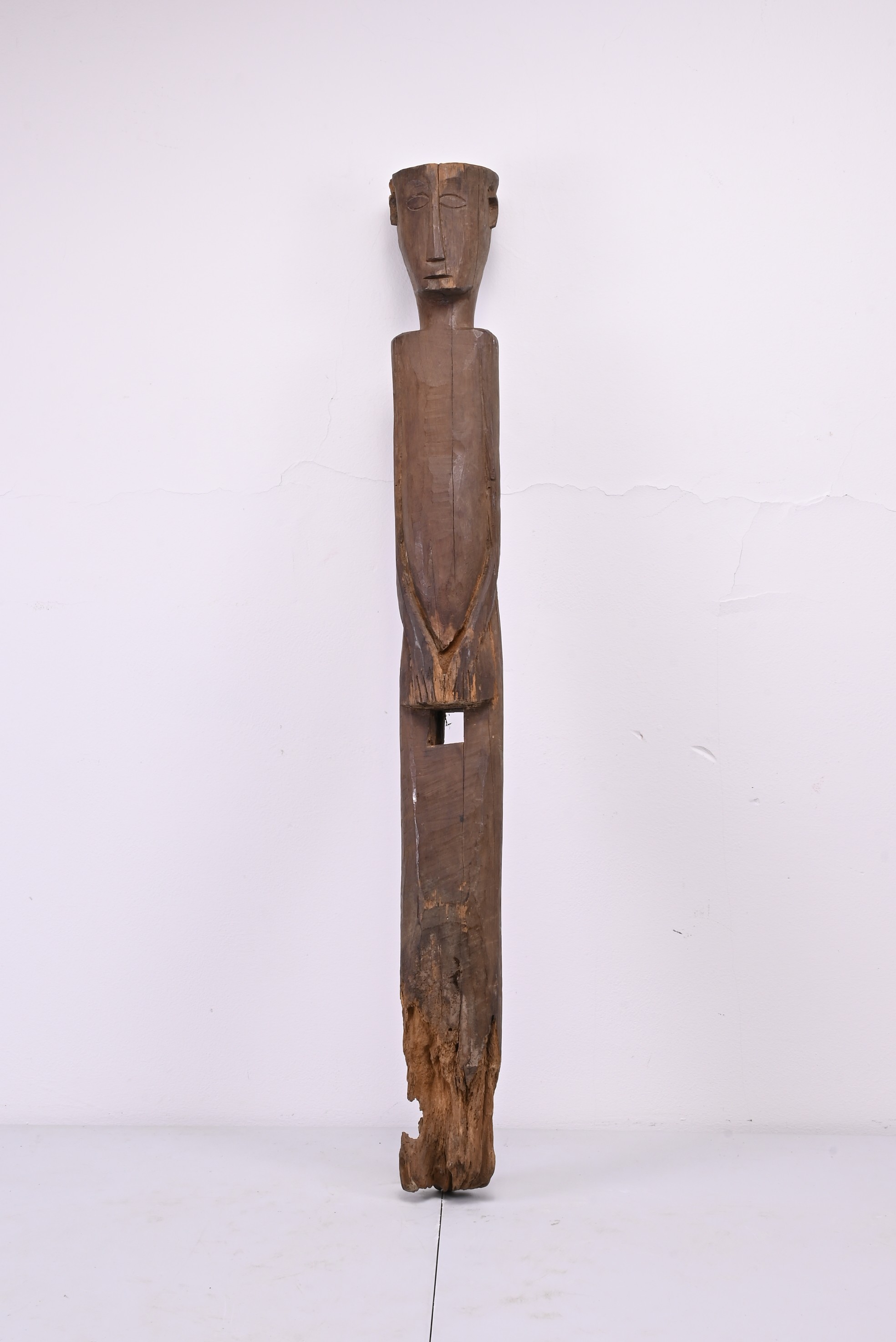 A TALL AFRICAN CARVED WOODEN FIGURE. A slender human figure with hands clasp in front of the