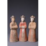 THREE CHINESE PAINTED POTTERY FIGURES OF ATTENDANTS, TANG DYNASTY (AD 618-907). Modelled standing