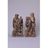 A PAIR OF 20TH CENTURY CARVED SOAPSTONE FIGURES OF A SAGE AND ATTENDANT. Each in mottled dark