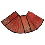 A CHINESE EMBROIDERED CORAL RED SILK SKIRT, EARLY 20TH CENTURY. Pleated and edged in black,