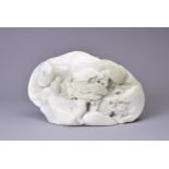 A CARVED PALE JADE BOULDER. Carved with two figures standing on pierced rockwork and trees, with