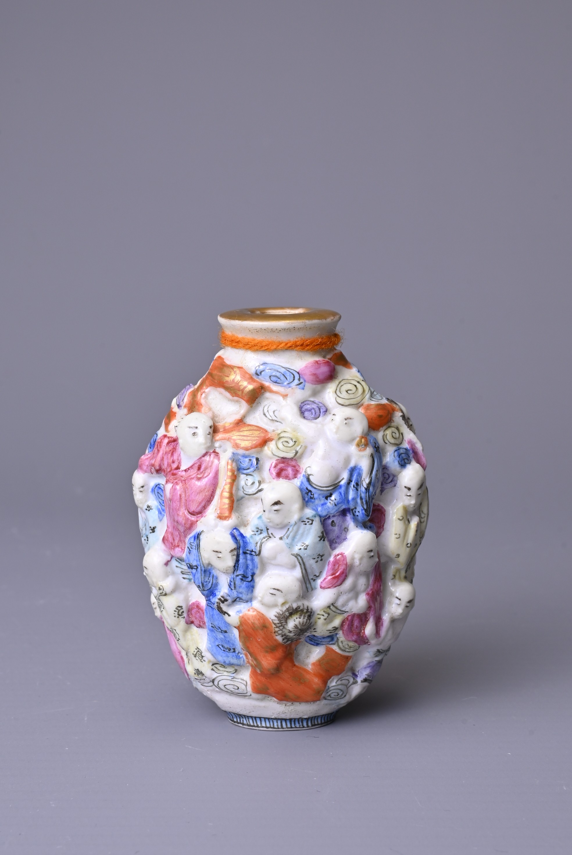 A CHINESE FAMILLE ROSE PORCELAIN SNUFF BOTTLE, 19TH CENTURY. Moulded with the Eighteen Luohan