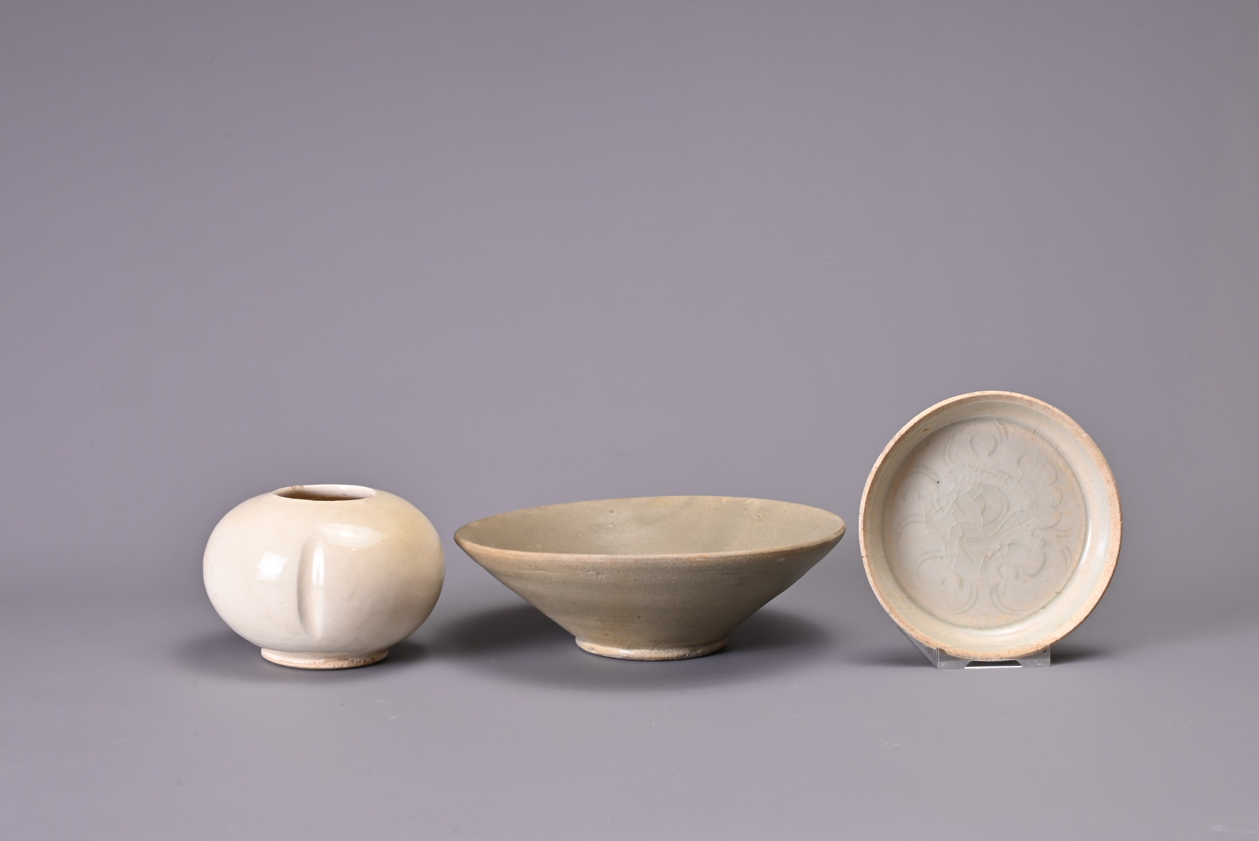 THREE CHINESE CELADON ITEMS. Comprising: a Tang Dynasty (AD 618-907) flared bowl, in dark green