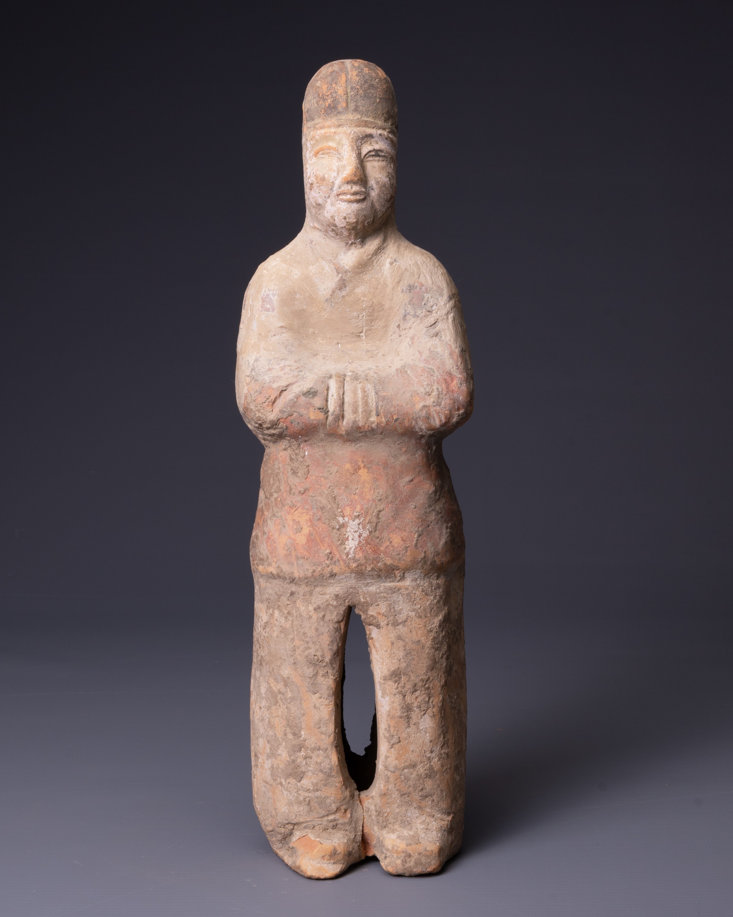 A CHINESE PAINTED POTTERY FIGURE OF AN ATTENDANT, TANG DYNASTY (AD 618-907). Modelled standing