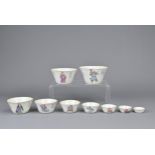 A SET OF NINE CHINESE FAMILLE ROSE PORCELAIN GRADUATING CUPS, LATE QING DYNASTY. Each decorated to