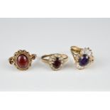 TWO 9KT YELLOW GOLD STONE SET RINGS AND A YELLOW METAL DRESS RING. The first with oval garnet