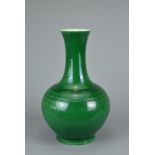 A CHINESE GREEN GLAZED BOTTLE VASE, 20TH CENTURY. Globular body with tall tapered neck decorated