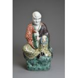 A CHINESE POLYCHROME DECORATED PORCELAIN FIGURE OF LUOHAN, EARLY 20TH CENTURY. The male figure