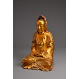 A CHINESE RED LACQUER AND GILT WOOD FIGURE OF GUANYIN. The figure seated in dhyanasana dressed in