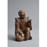 A JAPANESE MEIJI PERIOD (1868-1912) CARVED HUANG YANG WOOD OKIMONO OF A SEATED GENTLEMAN. Seated